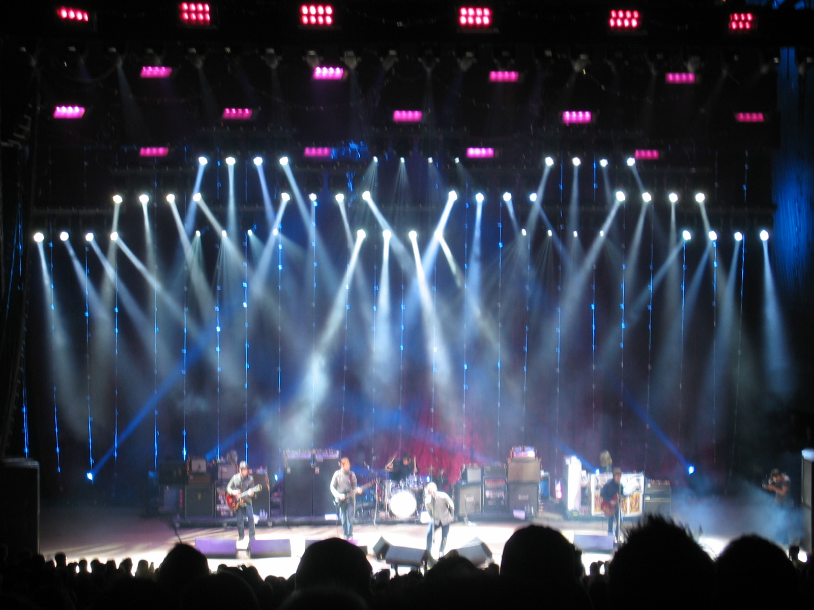 Oasis performing to a stadium crowd under stage lighting